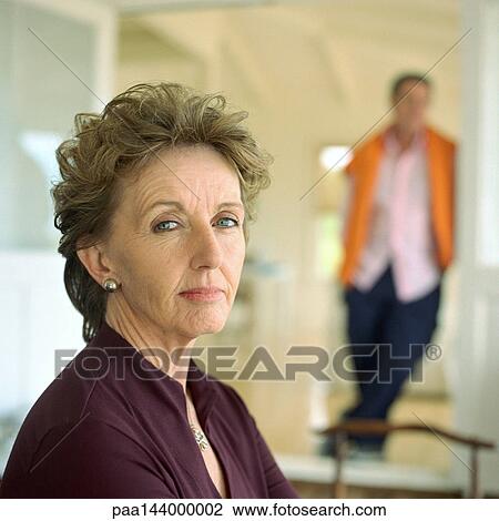 Mature woman looking into camera, man standing behind her, portrait View Large Photo Image Stock Image - Mature woman looking into camera, man standing behind her, portrait. Fotosearch