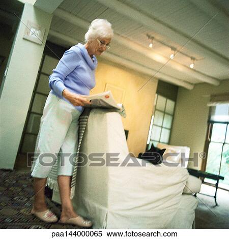 Mature woman standing in living room, reading View Large Photo Image Stock Photography - Mature woman standing in living room, reading. Fotosearch