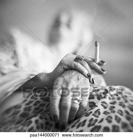 Mature woman's hands holding cigarette, low angle view, b&w View Large Photo Image Stock Image - Mature woman's hands holding cigarette, low angle view, b&w. Fotosearch