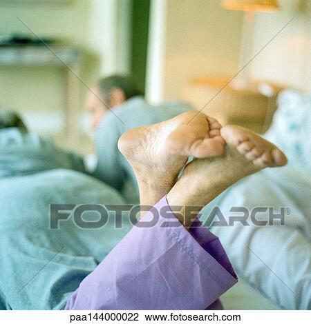 Two people lying on stomach side by side, focus on feet View Large Photo Image Stock Image - Two people lying on stomach side by side, focus on feet. Fotosearch