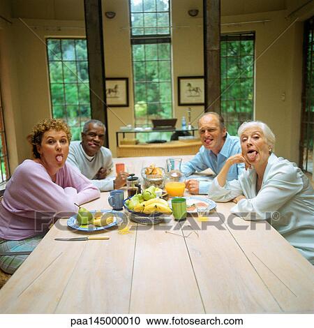 Four mature people sitting at table, sticking out tongues View Large Photo Image Stock Image - Four mature people sitting at table, sticking out tongues. Fotosearch
