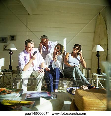 Picture - Four people side by side, using phones. Fotosearch