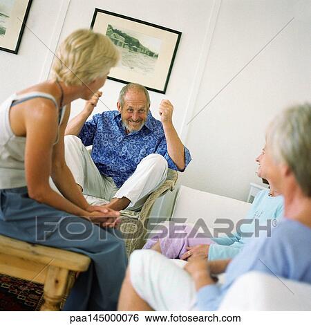 Four people sitting in a room, man raising arms and knees View Large Photo Image Stock Photograph - Four people sitting in a room, man raising arms and knees. Fotosearch