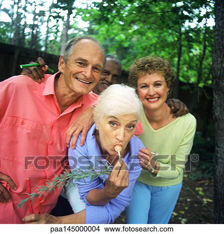 Four people standing outdoors, woman sucking lollipop View Large Photo Image Picture - Four people standing outdoors, woman sucking lollipop. Fotosearch
