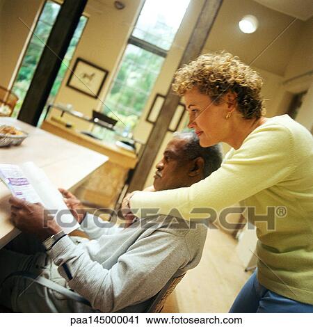 Man sitting at table, woman standing with arms around him, side view View Large Photo Image Stock Image - Man sitting at table, woman standing with arms around him, side view. Fotosearch