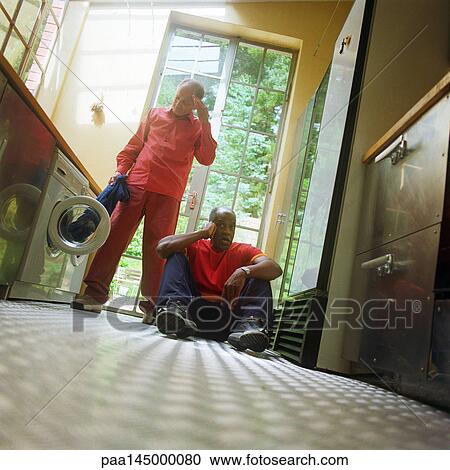 Man sitting on floor, other man taking garment out of washer View Large Photo Image Stock Image - Man sitting on floor, other man taking garment out of washer. Fotosearch