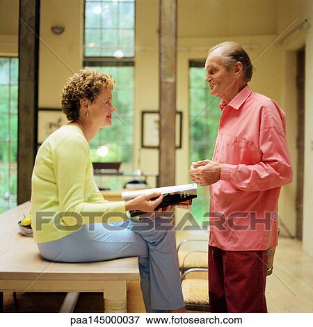 Mature couple face to face, woman sitting on table, man standing, side view View Large Photo Image Stock Photo - Mature couple face to face, woman sitting on table, man standing, side view. Fotosearch