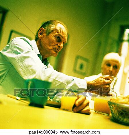 Mature couple sitting at table, man holding pitcher View Large Photo Image Stock Photography - Mature couple sitting at table, man holding pitcher. Fotosearch