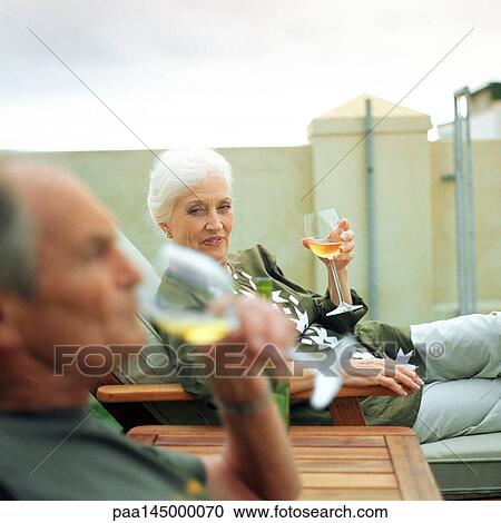 Mature man and woman having a drink outside, focus on woman in background View Large Photo Image Stock Image - Mature man and woman having a drink outside, focus on woman in background. Fotosearch