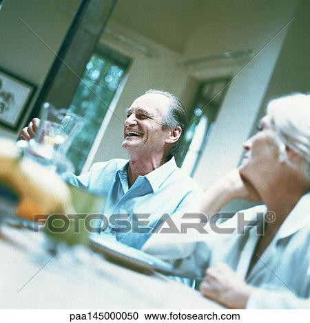 Stock Image - Mature man and woman sitting at table. Fotosearch