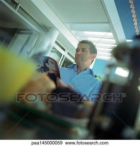 Mature man looking at magazine, blurred foreground View Large Photo Image Stock Photo - Mature man looking at magazine, blurred foreground. Fotosearch
