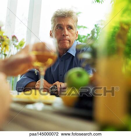 Mature man sitting at table View Large Photo Image Stock Image - Mature man sitting at table. Fotosearch