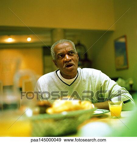 Stock Photo - Mature man sitting at table. Fotosearch