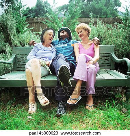 Mature man sitting between two women on bench View Large Photo Image Stock Image - Mature man sitting between two women on bench. Fotosearch