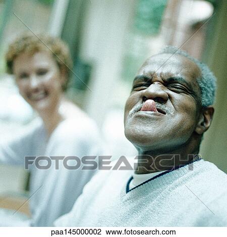 Mature man sticking out tongue, woman smiling in background View Large Photo Image Stock Image - Mature man sticking out tongue, woman smiling in background. Fotosearch