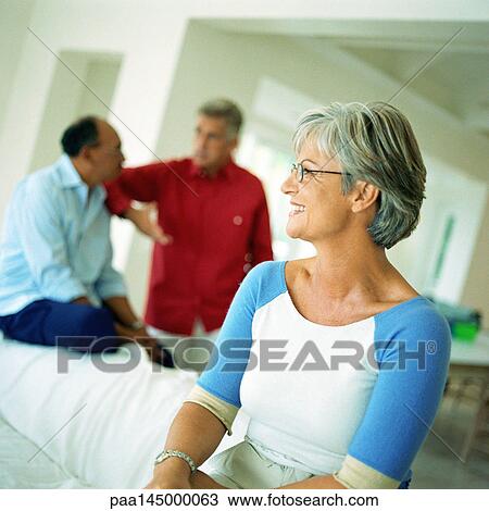 Mature woman smiling, two men in background View Large Photo Image Stock Image - Mature woman smiling, two men in background. Fotosearch