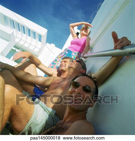 Three bare-chested men and a woman leaning against wall View Large Photo Image Stock Photo - Three bare-chested men and a woman leaning against wall. Fotosearch