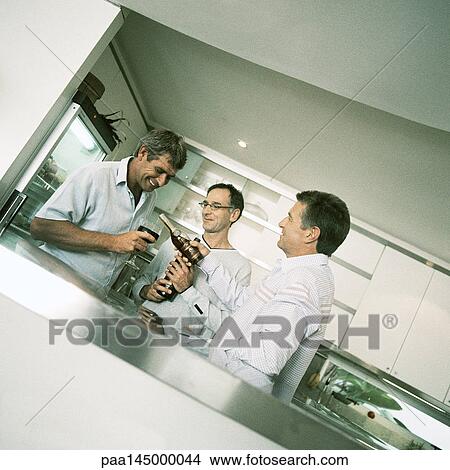 Three men having a drink in kitchen View Large Photo Image Picture - Three men having a drink in kitchen. Fotosearch