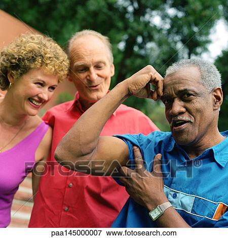 Three people standing outside, man flexing arm muscles View Large Photo Image Stock Photo - Three people standing outside, man flexing arm muscles. Fotosearch