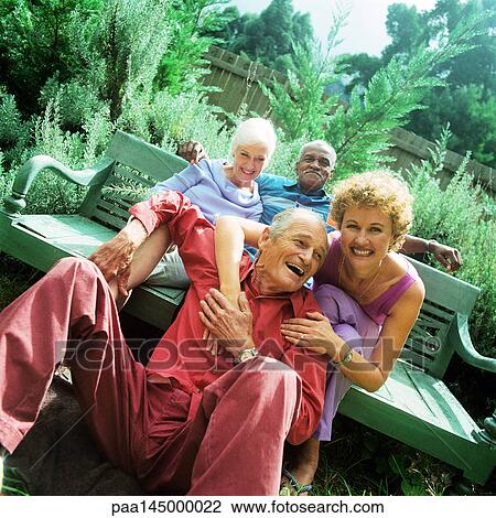 Two mature couples sitting outdoors, smiling View Large Photo Image Stock Image - Two mature couples sitting outdoors, smiling. Fotosearch
