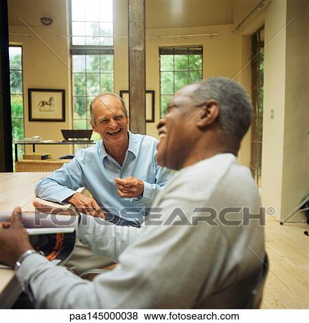Two mature men sitting at table, laughing View Large Photo Image Stock Photo - Two mature men sitting at table, laughing. Fotosearch