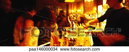 Bartender serving people at bar, blurred View Large Photo Image Picture - Bartender serving people at bar, blurred. Fotosearch