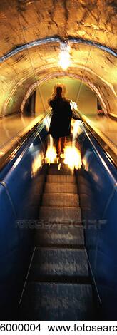 Picture - Woman riding escalator at night, rear view. Fotosearch