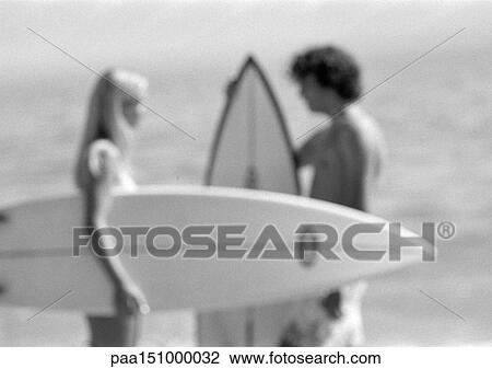 Couple holding surfboards, talking, blurred, b&w. View Large Photo Image Stock Image - Couple holding surfboards, talking, blurred, b&w. . Fotosearch
