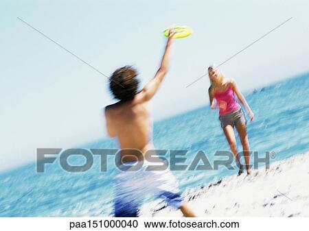 Couple on beach, man catching frisbee, blurred. View Large Photo Image Stock Image - Couple on beach, man catching frisbee, blurred.. Fotosearch