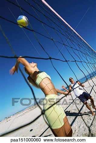 Couple playing beach volleyball, woman hitting ball over net. View Large Photo Image Stock Image - Couple playing beach volleyball, woman hitting ball over net.. Fotosearch