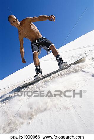 Stock Photograph - Man snowboarding, low angle view.. Fotosearch