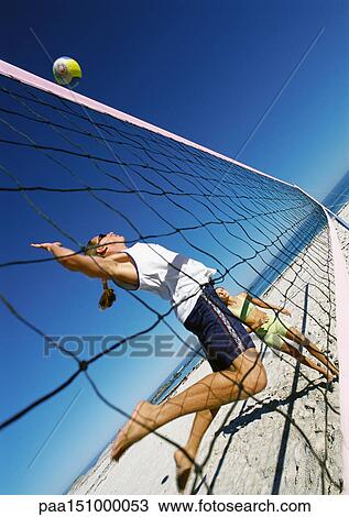 Two young women playing beach volleyball, one in mid-air. View Large Photo Image Stock Image - Two young women playing beach volleyball, one in mid-air.. Fotosearch