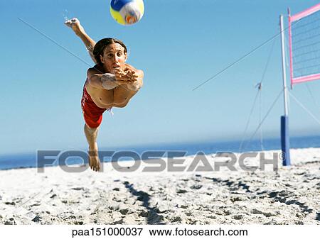 Young man jumping to hit volleyball, mid-air. View Large Photo Image Stock Photo - Young man jumping to hit volleyball, mid-air.. Fotosearch