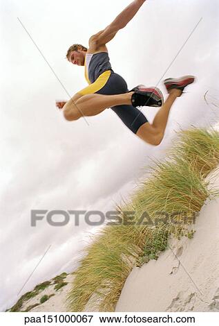 Young man on beach jumping, mid-air, low angle view. View Large Photo Image Stock Photo - Young man on beach jumping, mid-air, low angle view.. Fotosearch