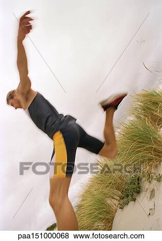 Young man on beach jumping, side view, low angle. View Large Photo Image Stock Photo - Young man on beach jumping, side view, low angle.. Fotosearch