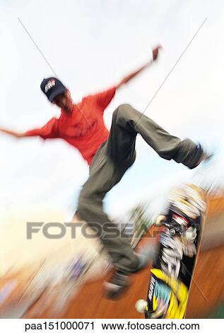 Young man on skateboard, jumping, mid-air, low angle. View Large Photo Image Stock Image - Young man on skateboard, jumping, mid-air, low angle.. Fotosearch