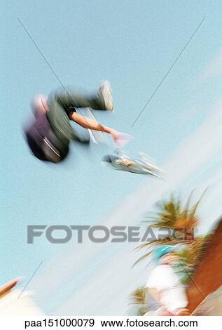 Young man on skateboard, jumping, mid-air, blurred, low angle view. View Large Photo Image Stock Photo - Young man on skateboard, jumping, mid-air, blurred, low angle view.. Fotosearch