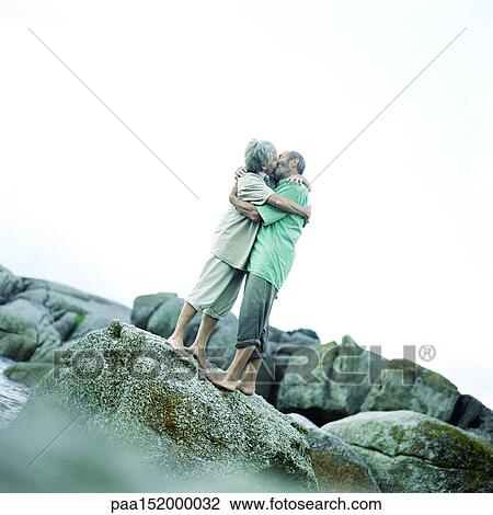 Mature couple kissing, standing on rocks. View Large Photo Image Stock Image - Mature couple kissing, standing on rocks. . Fotosearch