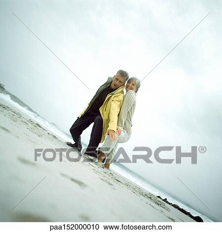 Mature couple on beach looking down into camera. View Large Photo Image Stock Image - Mature couple on beach looking down into camera. . Fotosearch