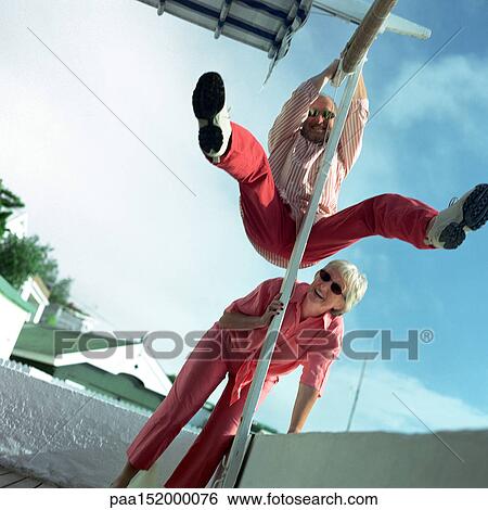 Mature couple playing, man swinging from pole. View Large Photo Image Stock Photograph - Mature couple playing, man swinging from pole.. Fotosearch
