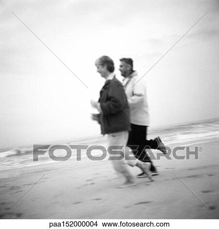 Mature couple running on beach, b&w. View Large Photo Image Picture - Mature couple running on beach, b&w.. Fotosearch