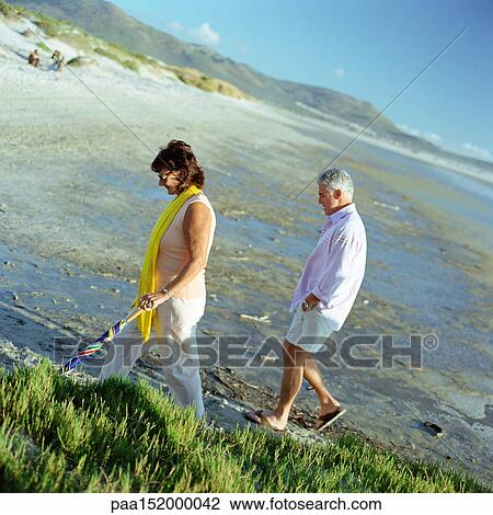 Mature couple walking on beach, side view. View Large Photo Image Stock Image - Mature couple walking on beach, side view.. Fotosearch