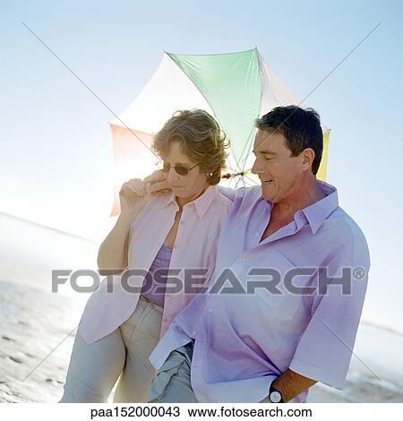 Mature couple walking with umbrella, portrait. View Large Photo Image Stock Image - Mature couple walking with umbrella, portrait.. Fotosearch
