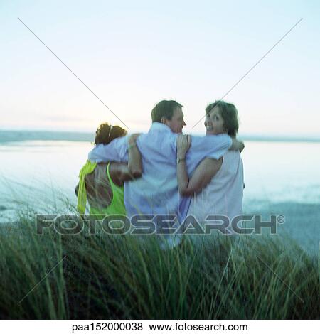 Mature friends with arms around each other, sitting on beach, rear view. View Large Photo Image Stock Photo - Mature friends with arms around each other, sitting on beach, rear view.. Fotosearch