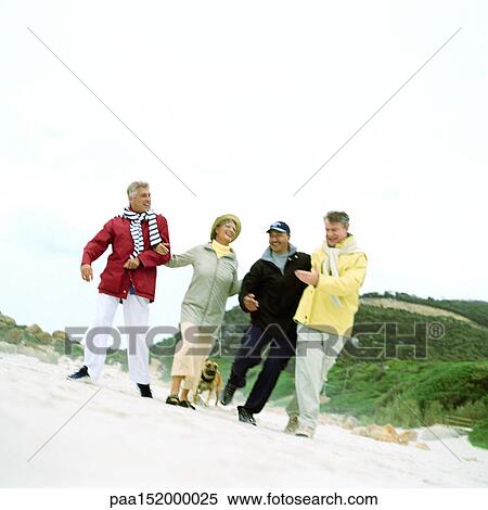 Stock Photography - Mature group of friends arm in arm on beach, portrait.. Fotosearch