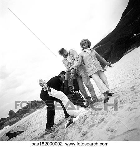 Stock Image - Mature group playing on beach, b&w.. Fotosearch