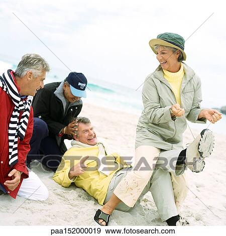 Mature group playing on beach, woman pulling man's laces. View Large Photo Image Stock Photo - Mature group playing on beach, woman pulling man's laces. . Fotosearch