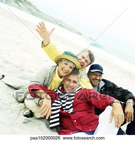 Stock Photograph - Mature group sitting on beach looking into camera.. Fotosearch