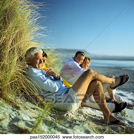 Stock Photography - Mature group sitting on beach.. Fotosearch