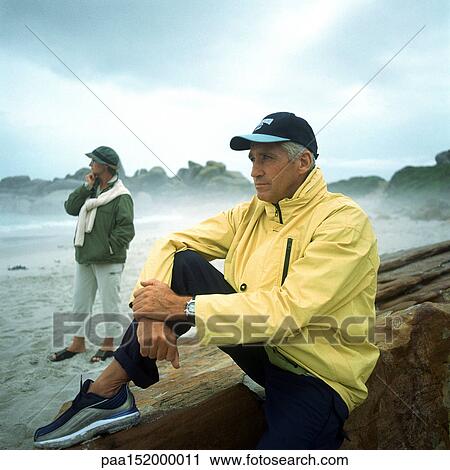 Mature man sitting and mature woman standing on beach. View Large Photo Image Stock Image - Mature man sitting and mature woman standing on beach.. Fotosearch